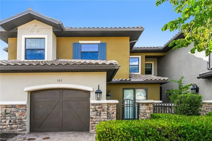 View of front of home featuring stone siding, stucco siding, a tile roof, and driveway