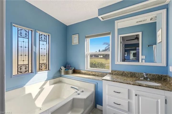 Bathroom with a garden tub, vanity, a textured ceiling, and crown molding