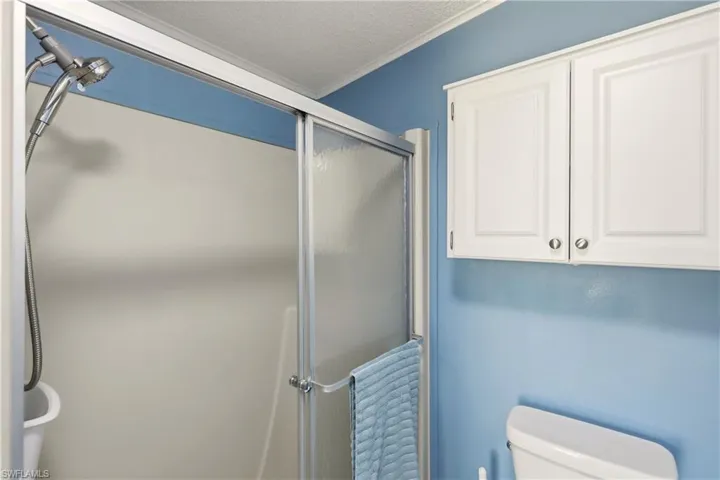 Full bathroom with a stall shower, a textured ceiling, and crown molding