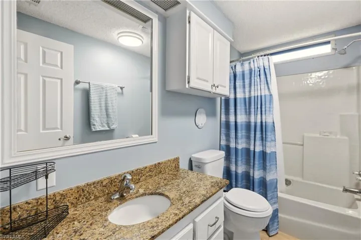 Bathroom featuring shower / bath combo, vanity, and a textured ceiling