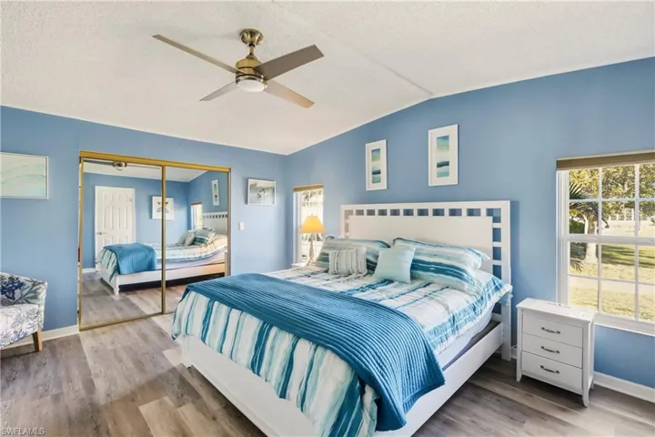 Bedroom featuring light wood-style floors, ceiling fan, a closet, lofted ceiling, and a textured ceiling