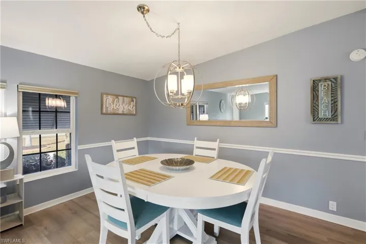 Dining area featuring wood finished floors, a chandelier, and vaulted ceiling