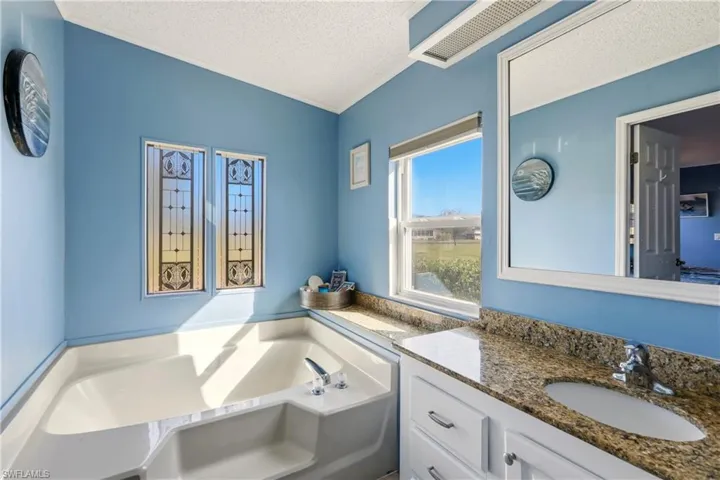 Bathroom with a textured ceiling, a garden tub, and vanity