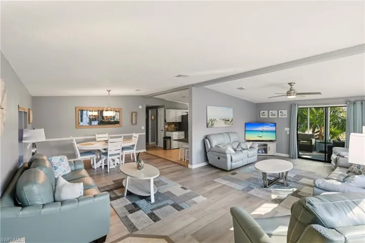 Living room with wood finished floors, lofted ceiling, and a ceiling fan