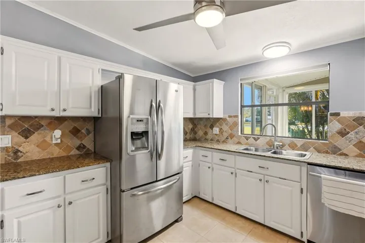 Kitchen featuring stainless steel appliances, white cabinets, dark stone counters, and crown molding