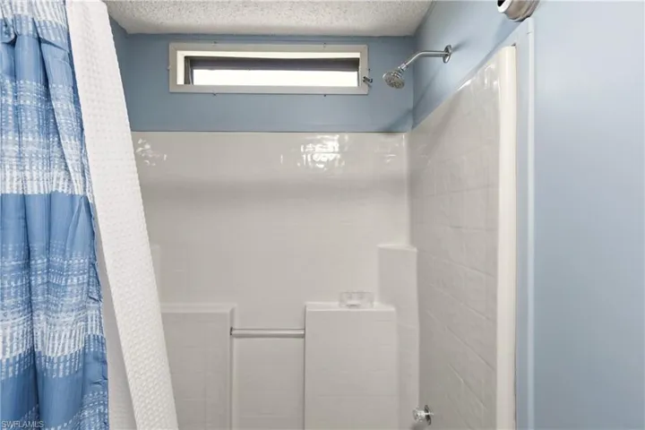 Bathroom featuring a tile shower and a textured ceiling