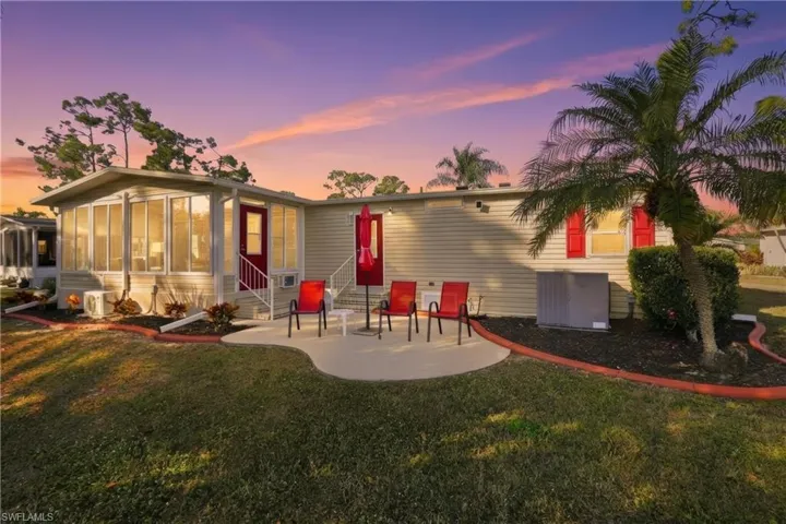 Back of property at dusk featuring entry steps, a sunroom, and a yard