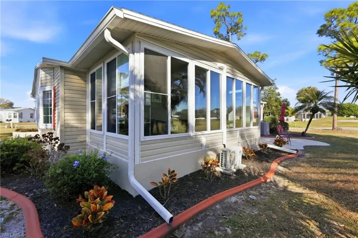 View of side of home featuring a sunroom and a cooling unit