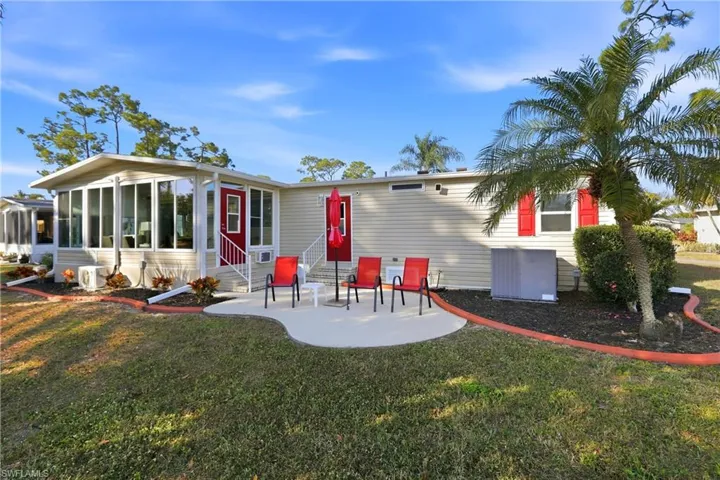 Rear view of property featuring a yard, a sunroom, entry steps, and a patio area