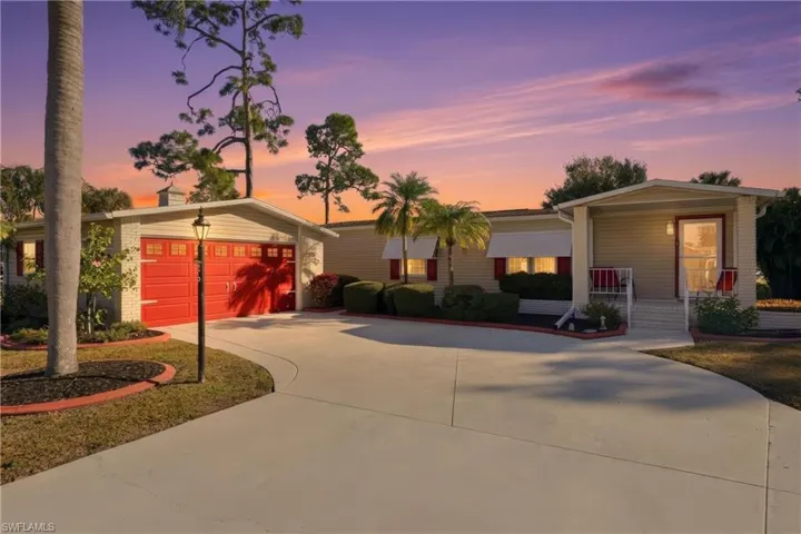 View of front of house featuring a garage, brick siding, driveway, and covered porch