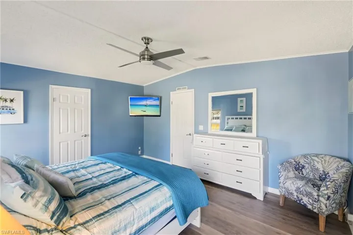 Bedroom with dark wood finished floors, a ceiling fan, vaulted ceiling, a textured ceiling, and ornamental molding