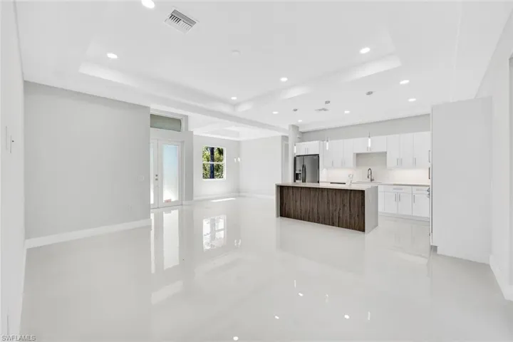 Kitchen with a raised ceiling, sink, light tile flooring, and stainless steel fridge with ice dispenser