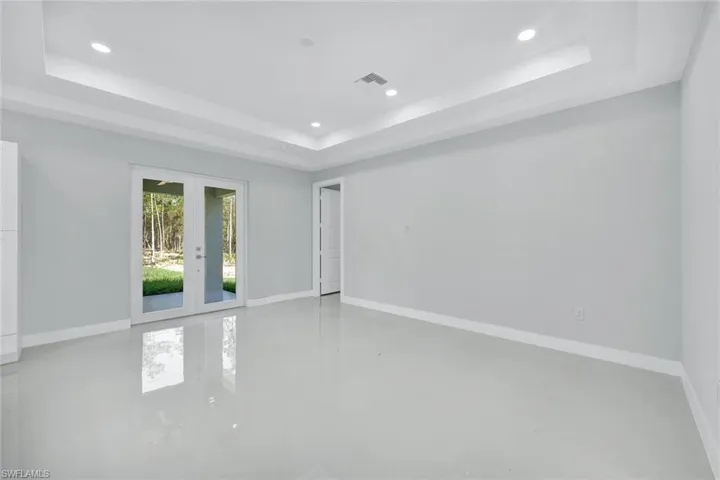 Tiled empty room with a tray ceiling and french doors