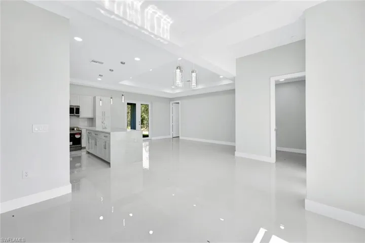 Unfurnished living room featuring light tile floors and a raised ceiling