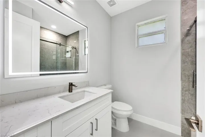 Bathroom with a shower with door, toilet, tile flooring, and oversized vanity