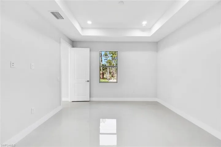 Tiled empty room featuring a tray ceiling