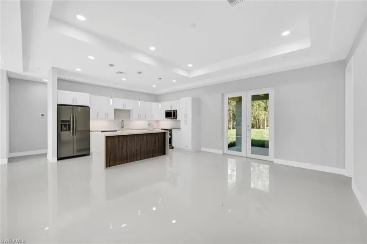 Kitchen with white cabinetry, french doors, appliances with stainless steel finishes, a tray ceiling, and sink