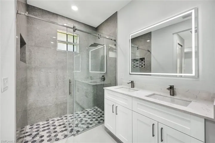 Bathroom with an enclosed shower, tile flooring, and double sink vanity