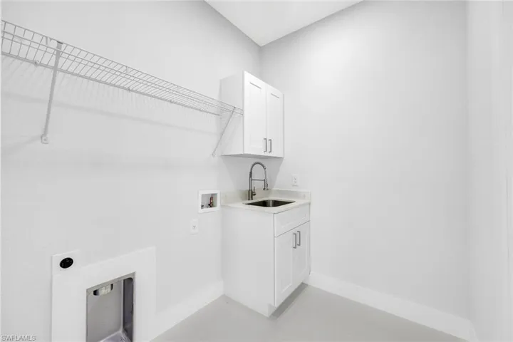 Clothes washing area with sink, washer hookup, electric dryer hookup, and cabinets
