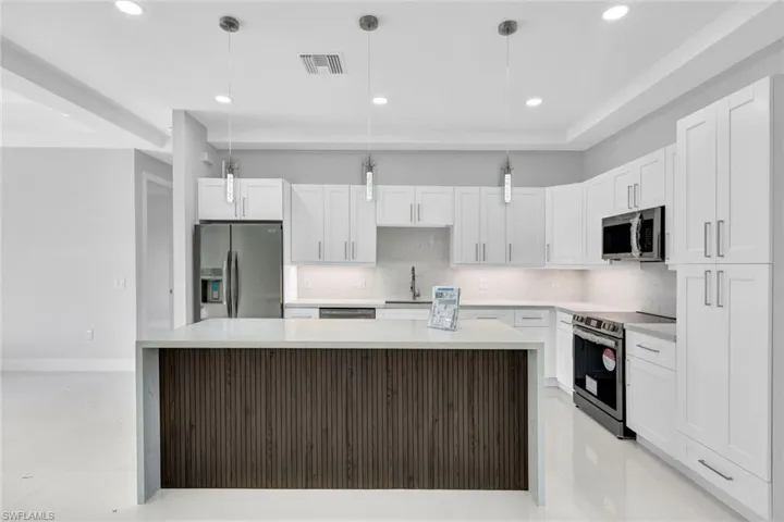 Kitchen with light tile flooring, tasteful backsplash, white cabinetry, appliances with stainless steel finishes, and pendant lighting