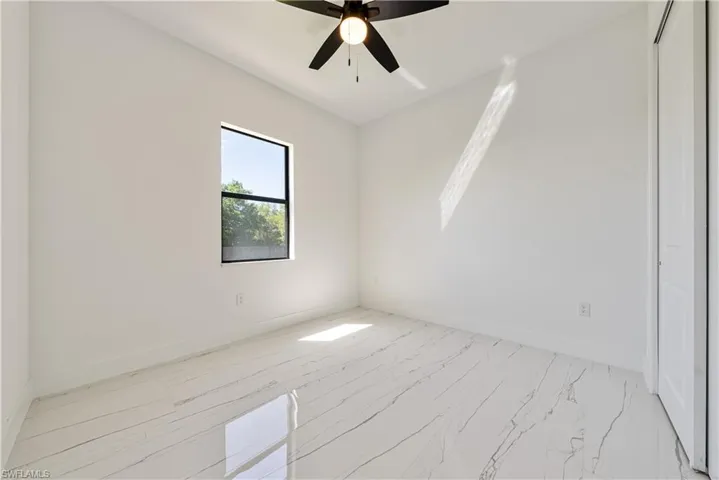 Unfurnished room featuring baseboards, marble finish floor, and a ceiling fan