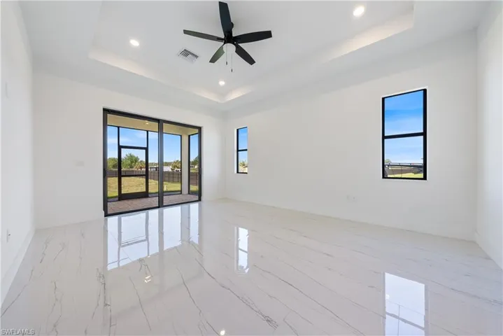 Unfurnished room featuring a raised ceiling, baseboards, visible vents, and ceiling fan