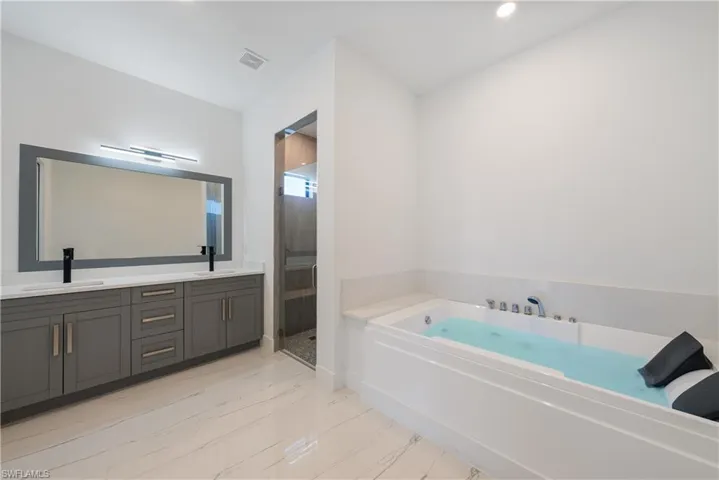 Full bathroom featuring double vanity, visible vents, a shower stall, and a sink