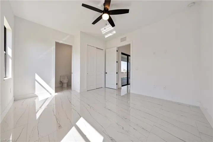 Unfurnished bedroom with visible vents, marble finish floor, a closet, baseboards, and ceiling fan