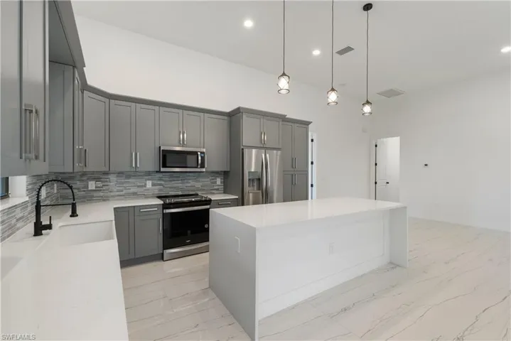 Kitchen featuring visible vents, marble finish floor, gray cabinetry, a sink, and stainless steel appliances