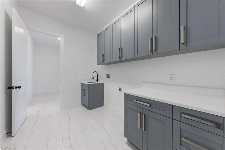 Laundry room with hookup for a washing machine, cabinet space, electric dryer hookup, a sink, and marble finish floor