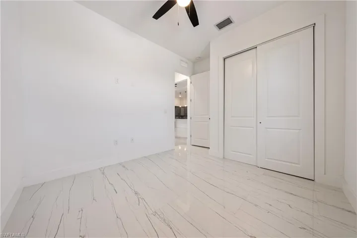 Unfurnished bedroom with a closet, visible vents, marble finish floor, and baseboards