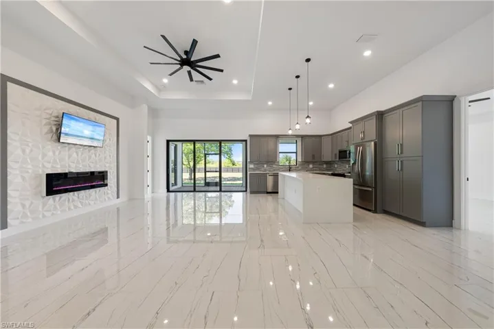 Kitchen with gray cabinets, a tray ceiling, open floor plan, stainless steel appliances, and light countertops