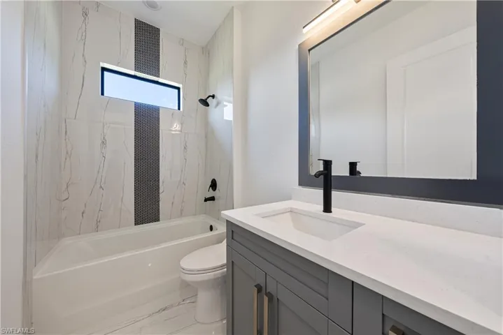 Bathroom featuring marble finish floor, toilet,  shower combination, and vanity