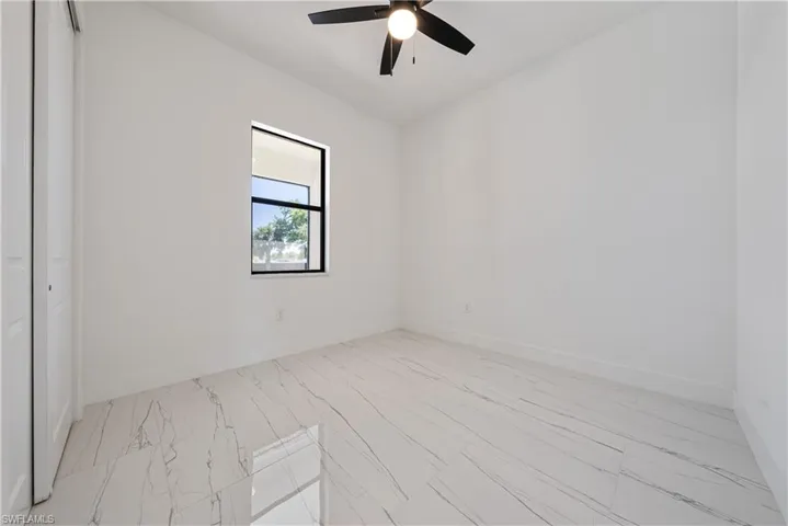Spare room featuring baseboards, marble finish floor, and ceiling fan