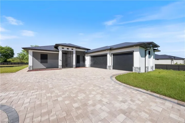 Prairie-style home with stucco siding, decorative driveway, stone siding, fence, and a garage