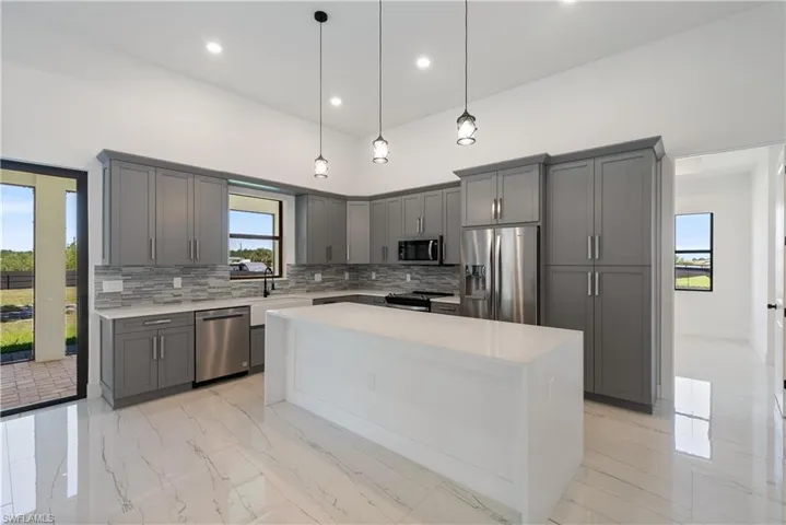 Kitchen featuring gray cabinetry, light countertops, appliances with stainless steel finishes, marble finish floor, and backsplash