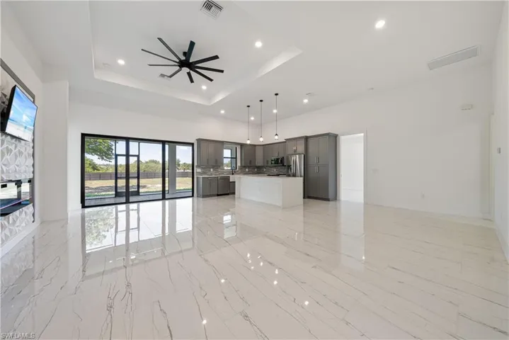Unfurnished living room with visible vents, a raised ceiling, a towering ceiling, and a ceiling fan