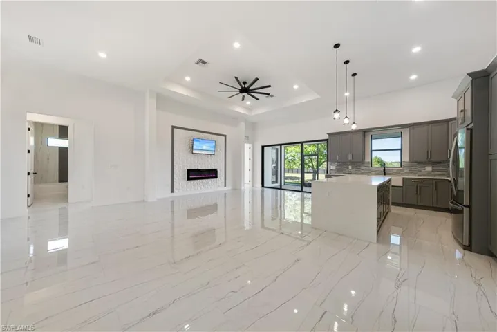 Kitchen featuring visible vents, gray cabinetry, a tray ceiling, open floor plan, and freestanding refrigerator