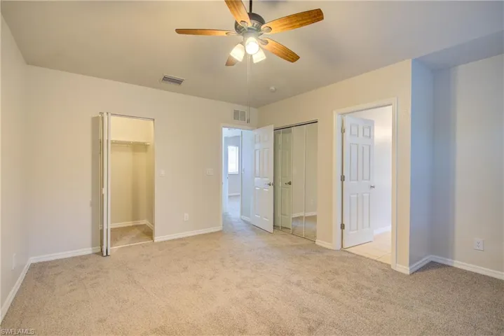 Unfurnished bedroom with ceiling fan and light carpet