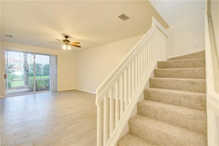 Stairway with hardwood / wood-style floors and ceiling fan