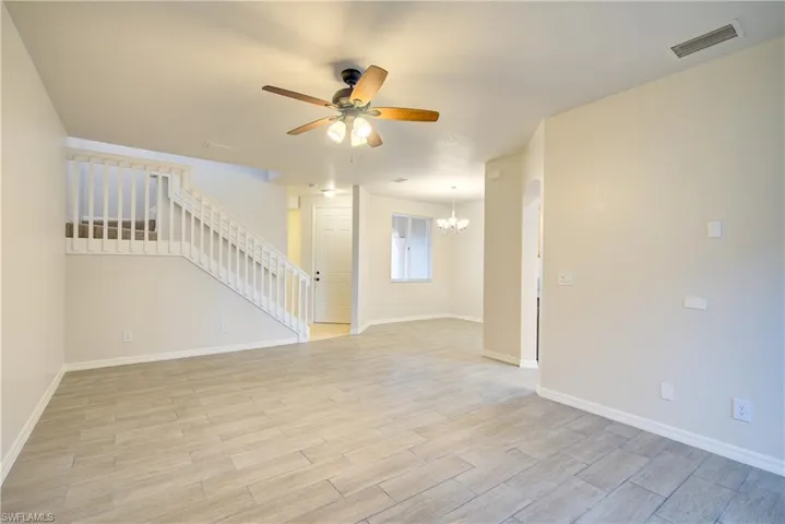 Empty room featuring ceiling fan with notable chandelier