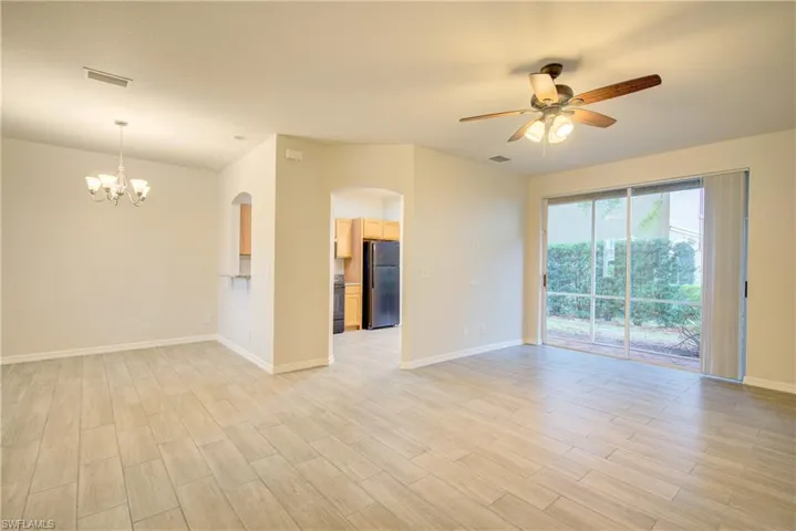 Unfurnished room featuring ceiling fan with notable chandelier and light hardwood / wood-style flooring