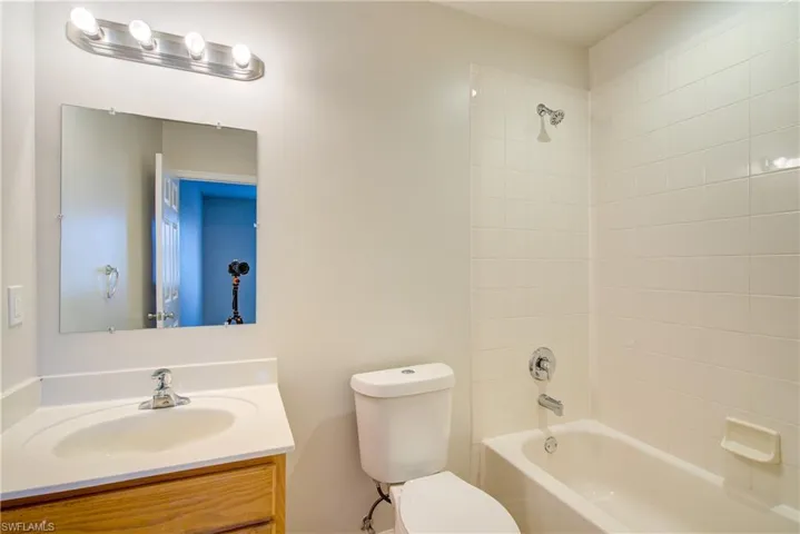 Full bathroom with tiled shower / bath, vanity, and toilet