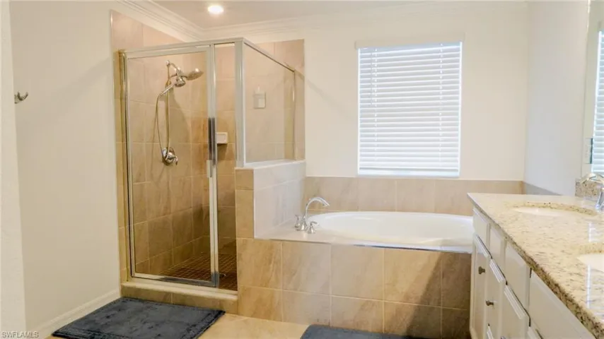 Bathroom with double vanity, ornamental molding, a stall shower, a bath, and tile patterned flooring