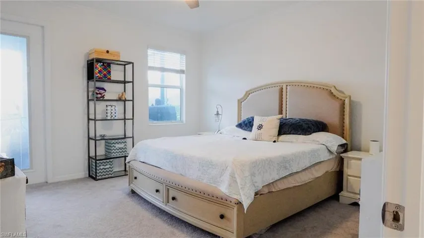 Bedroom with light carpet, ceiling fan, and ornamental molding