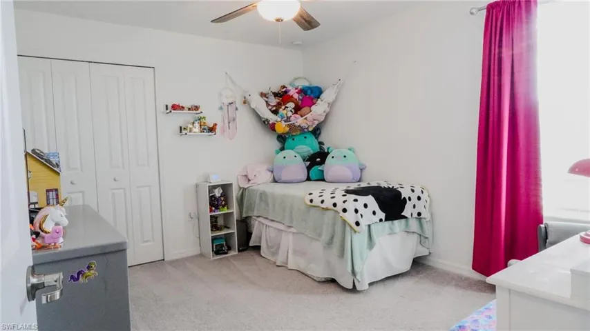 Bedroom with light carpet, a ceiling fan, and a closet