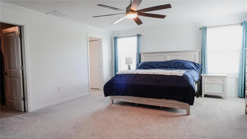 Bedroom featuring light colored carpet, ceiling fan, and crown molding