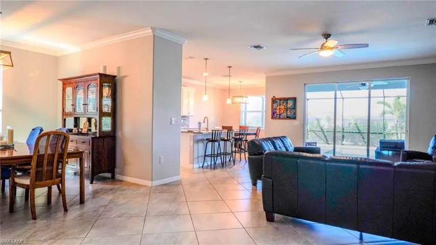 Living room featuring ornamental molding, a ceiling fan, and light tile patterned floors
