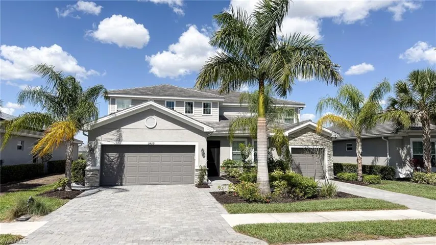 Traditional-style house with decorative driveway, stone siding, stucco siding, and a garage