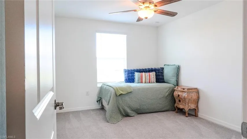 Bedroom with ceiling fan and light carpet